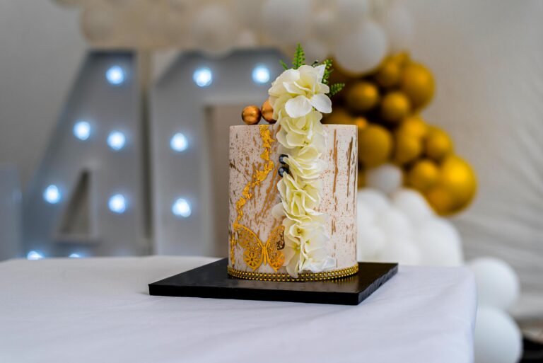 Explore this elegant birthday cake adorned with floral decorations and golden accents, perfect for celebrations.